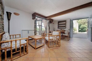 Ein Zimmer mit Steinwand, Holzboden und Fliesen. Es gibt Korbmöbel und einen Tisch.