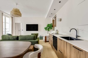 Een moderne keuken met een eethoek, een flatscreen televisie en een groot raam.