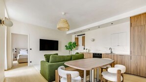 Una cucina moderna con zona pranzo, televisore a schermo piatto e divano verde.