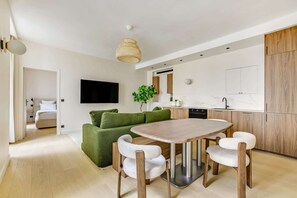 A modern kitchen with a dining area, a flat-screen TV, and a green sofa. - Gorgeous Air-conditioned 2-BR/2Ba  - Saint-Germain (Paris)