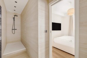 A modern bathroom with a shower, a toilet, and a bed with a white mattress. - Gorgeous Air-conditioned 2-BR/2Ba  - Saint-Germain (Paris)