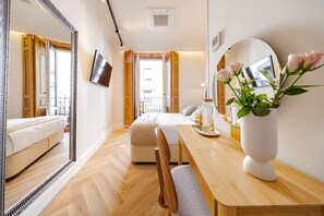 A hotel room with a bed, a wooden desk, a mirror, and a vase with flowers. - Alistana Boutique Gran Vía   (Madrid)