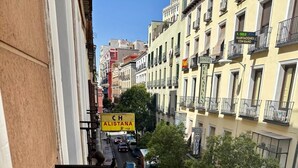 Una calle estrecha con coches aparcados y edificios a ambos lados. Se ven carteles de un hotel y un negocio.