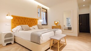 Una camera da letto con un grande letto, comodini, una panca, uno specchio e una porta.