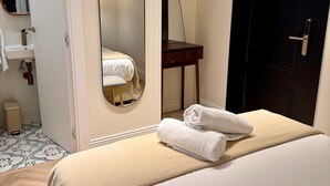 Una habitación de hotel con una cama, un espejo, un televisor, una puerta y una mesita.