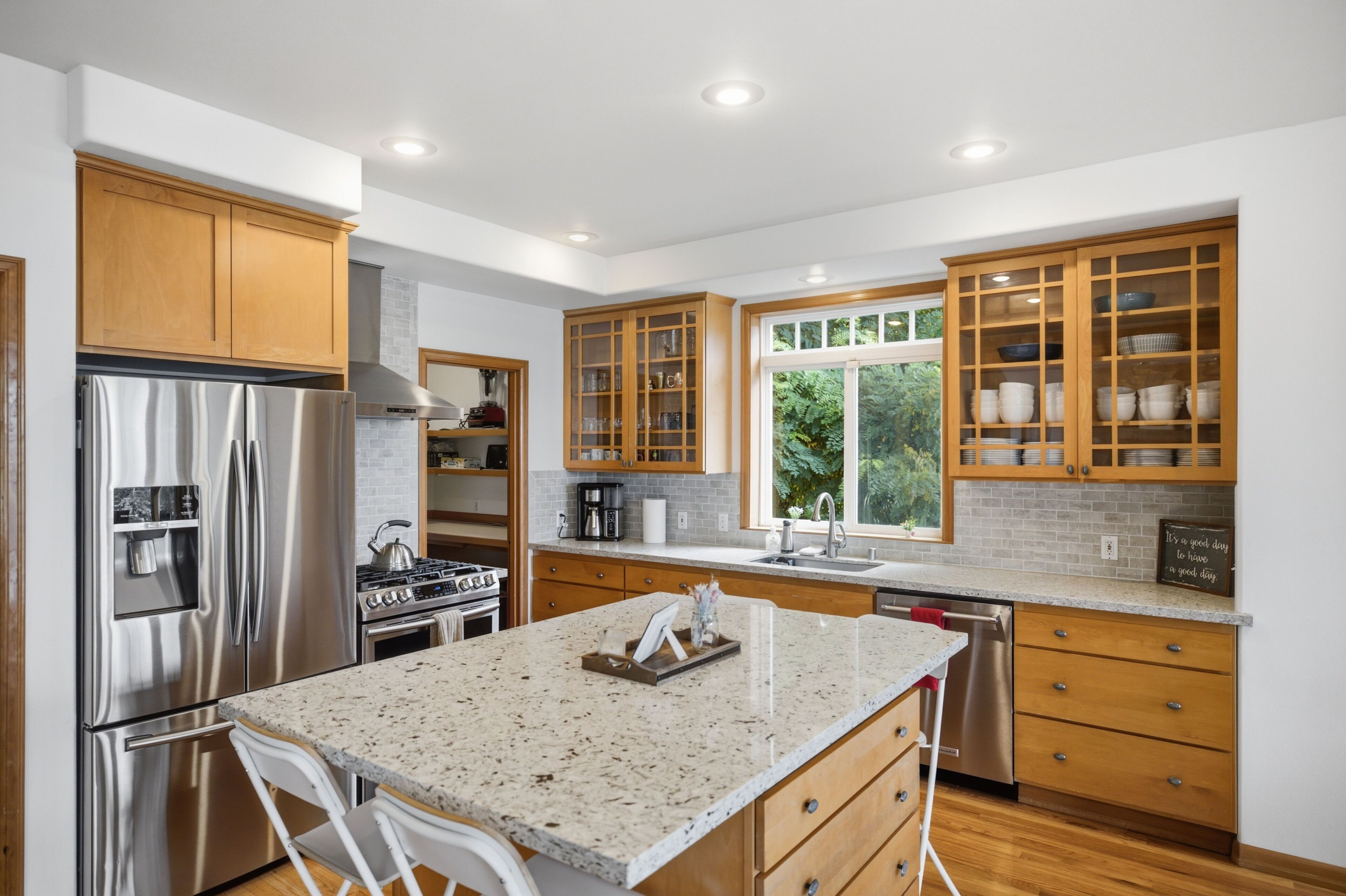 Una cocina moderna con electrodomésticos de acero inoxidable, gabinetes de madera y una encimera de granito.