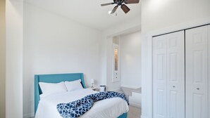 Ein Schlafzimmer mit einem Bett, einem Nachttisch, einem Deckenventilator und einem Kleiderschrank.