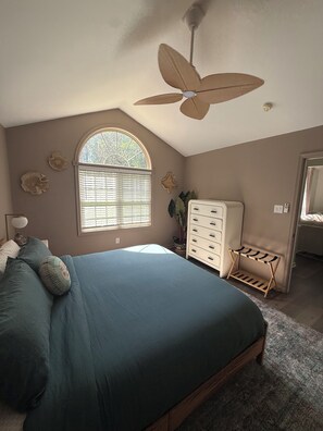 A bedroom with a bed, a dresser, a ceiling fan, and a window with blinds. - Livin' La Vida Lakehouse (Henrico)