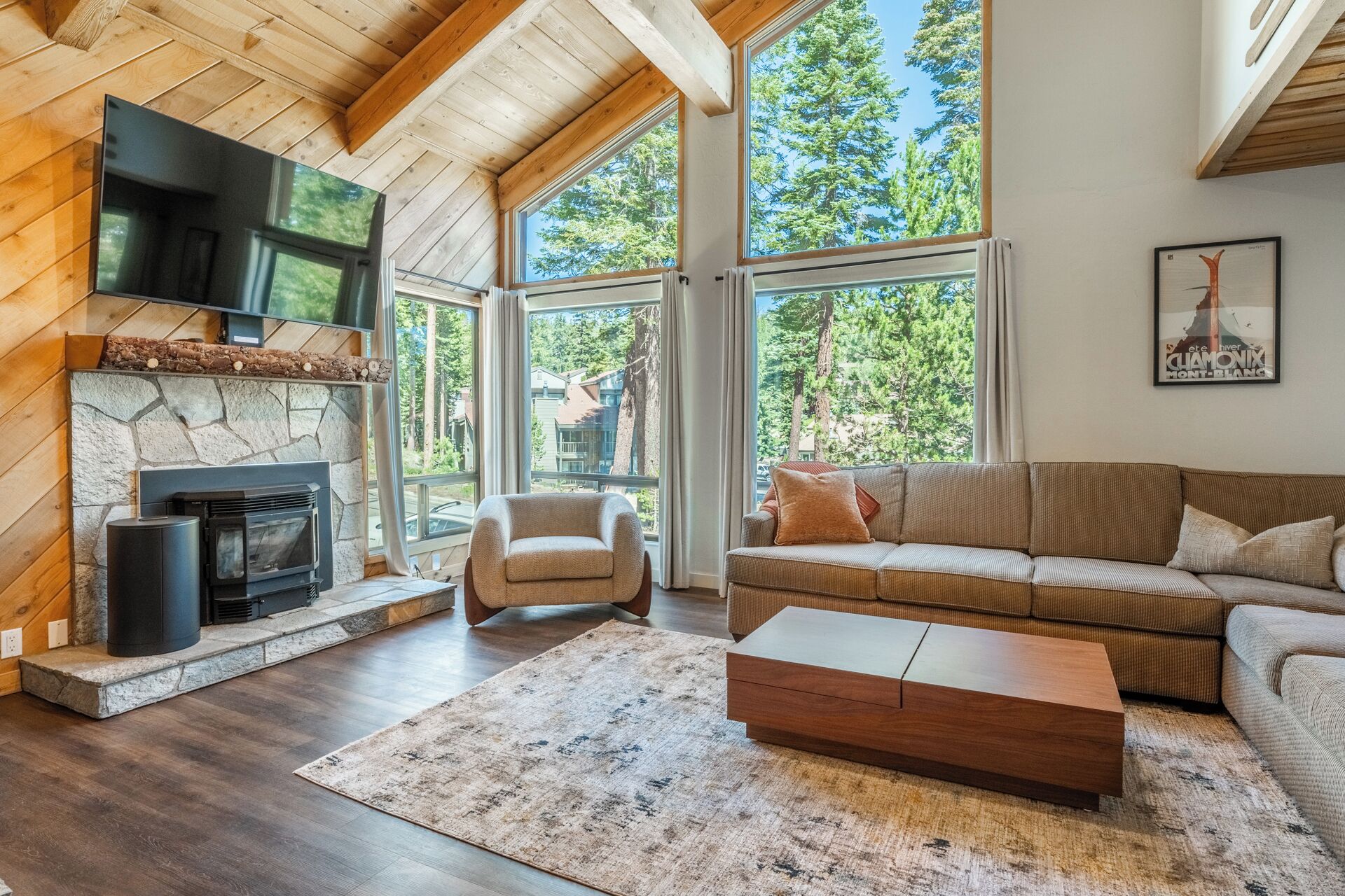 A modern living room with a stone fireplace, a flat-screen TV, a sofa, and a coffee table.