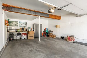 A garage with a concrete floor, a refrigerator, and various items including boxes and a fan. - Beautiful updated Courchevel by the Slopes. Sleeps up to 8 guests! (Mammoth Lakes)