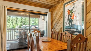 Ein Holzespeisetisch mit Stühlen, eine Glastür, die nach draußen führt, und ein Poster an der Wand.