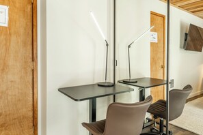 Ein Zimmer mit zwei Schreibtischen, zwei Stühlen und zwei Stehlampen.