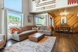 A spacious living area with a large sectional sofa, a wooden coffee table, and a dining table with chairs. - Beautiful updated Courchevel by the Slopes. Sleeps up to 8 guests! (Mammoth Lakes)