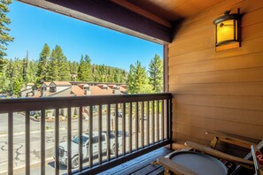 Un balcon en bois donnant sur un parking et des immeubles.