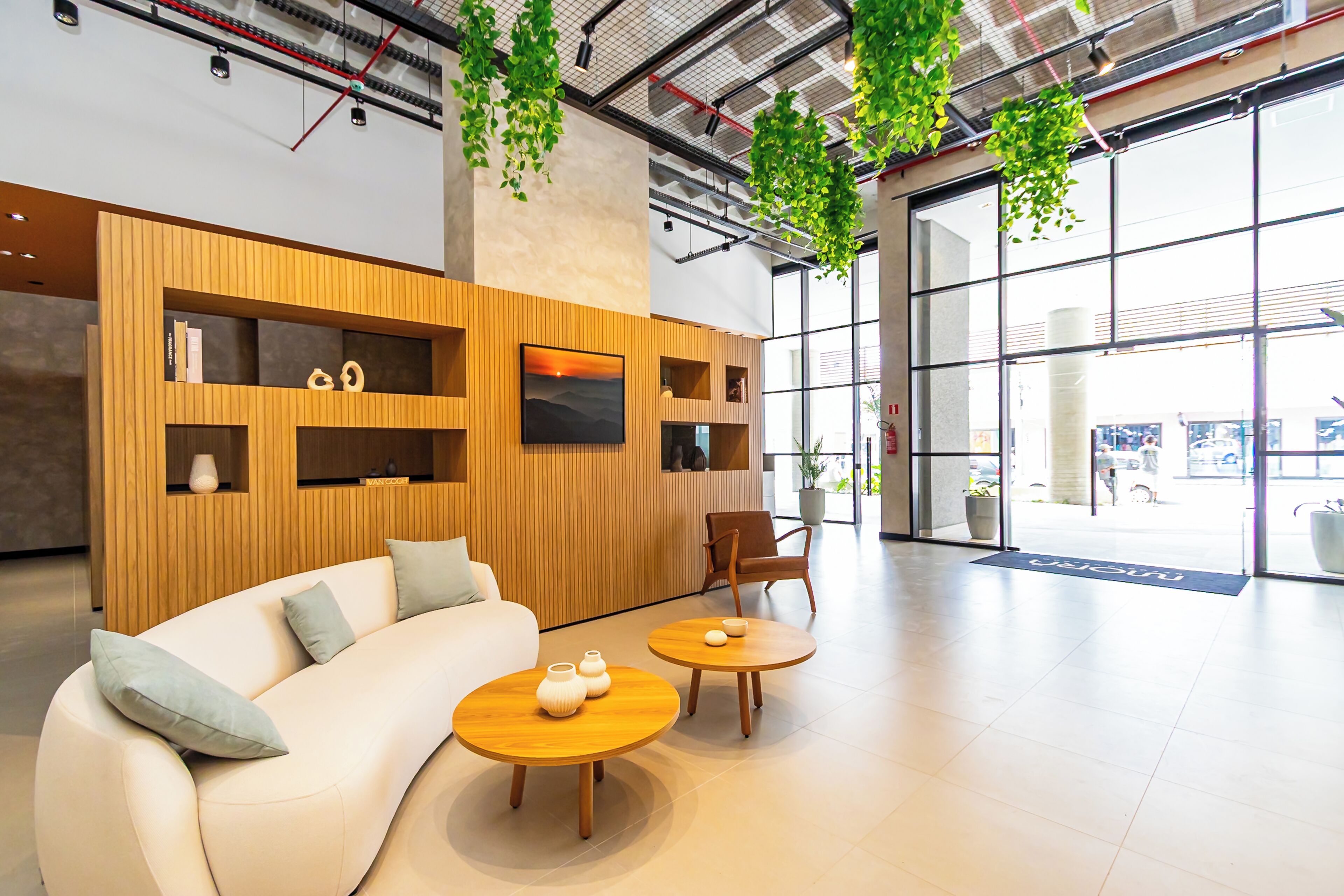 A modern interior with a sofa, two wooden tables, and hanging plants.