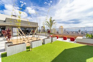 Un jardin sur le toit, agrémenté de jardinières, de sièges et offrant une vue sur le paysage urbain.