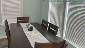 A dining room with a wooden table and chairs, a decorative centerpiece, and a window with a curtain. - Cozy 1-bedroom tiny home in resort setting (Citra)