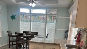 A kitchen with a central island, white cabinets, and a granite countertop. - Cozy 1-bedroom tiny home in resort setting (Citra)