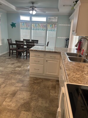A kitchen with a central island, white cabinets, and a granite countertop.