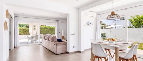 Un interior moderno con comedor, sofá y vistas al exterior.