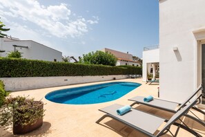 A swimming pool with lounge chairs and a potted plant. - VILLA MAGDALENA in Cala Blanca (Cala Blanca)