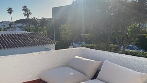 Eine Dachterrasse mit einer Couch und einem Holztisch, umgeben von einem gemusterten Teppich.
