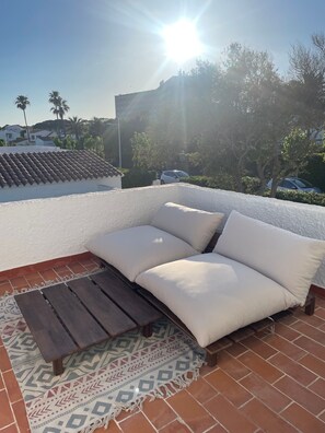 A rooftop terrace with a sofa and a wooden table, surrounded by a patterned rug. - House with sea views and pool 100 m from the coast in S'Algar (S'Algar)