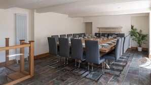 A dining room with a long table set for a meal, surrounded by chairs. - Finest Retreats | Serenity (Painswick)