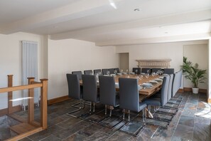 Ein Esszimmer mit einem langen Tisch, der für eine Mahlzeit gedeckt ist, umgeben von Stühlen.