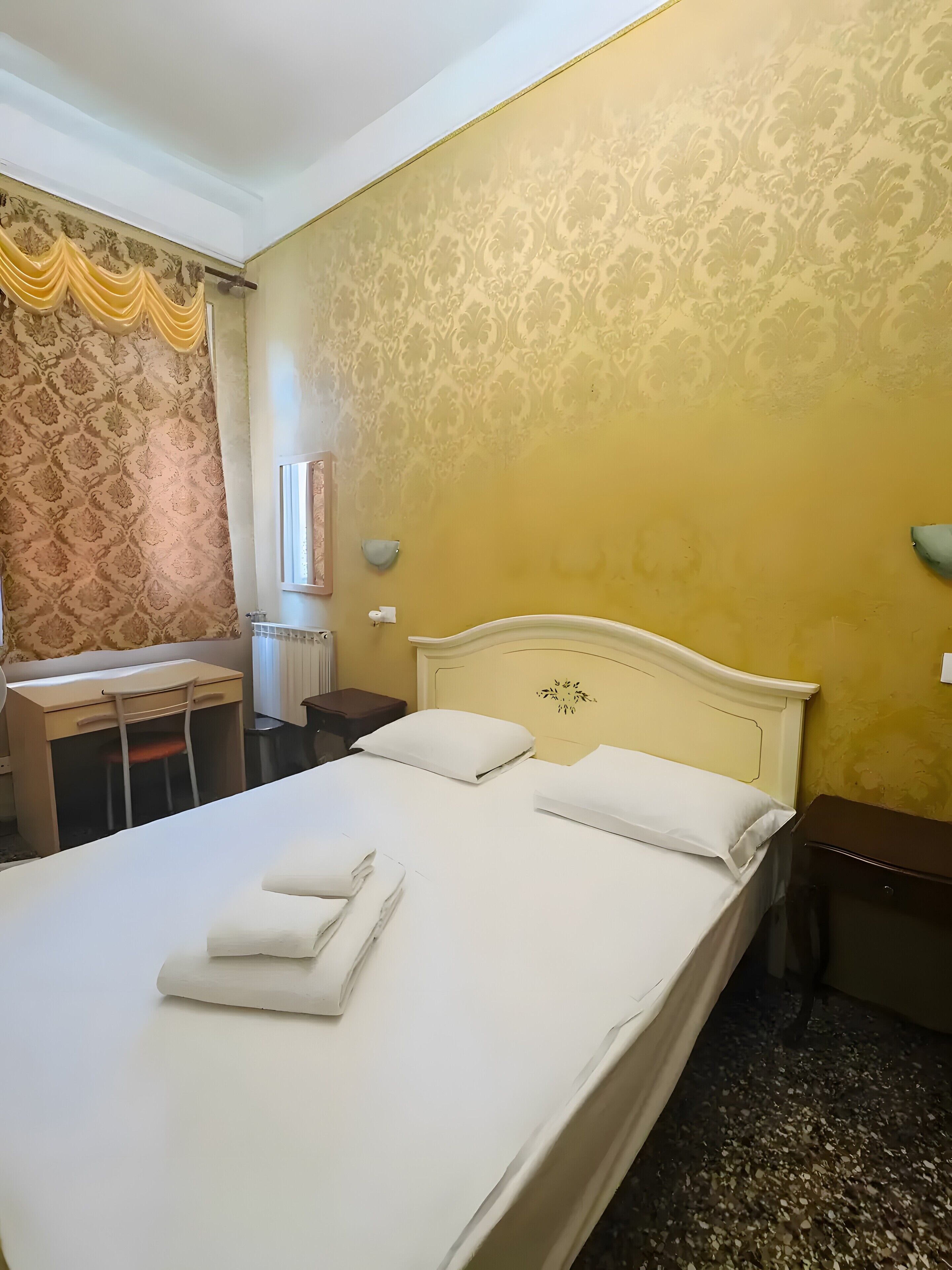 Une chambre d’hôtel avec un lit, un bureau et une chaise.