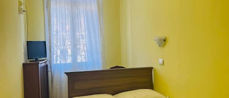 A room with a bed, a desk with a computer, a chandelier, and an air conditioning unit.