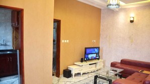 A living room with a television, a red sofa, a coffee table, and a patterned rug.
