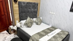 A bed with a tufted headboard, patterned bedding, and a black furry rug.