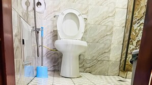 A bathroom with a toilet, a shower, and a yellow rug.