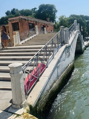 Eine Stebrücke mit Metallgeländern und Stufen, die zu einem Gebäude führen.