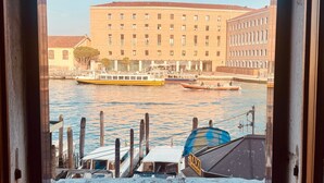 A view of a river with boats, a building with multiple windows, and a dock with a boat. - Room 'Ca Pisani Su Canal Grande Azzuro' with Wi-Fi (Venice)