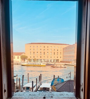 A view of a river with boats, a building with multiple windows, and a dock with a boat. - Room 'Ca Pisani Su Canal Grande Azzuro' with Wi-Fi (Venice)