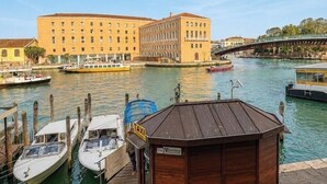 A waterfront view with a docked boat, a wooden structure labeled 'TAXI', and a large building in the background. - Room 'Ca Pisani Su Canal Grande Azzuro' with Wi-Fi (Venice)