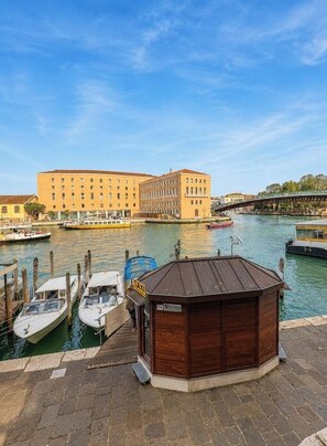 A waterfront view with a docked boat, a wooden structure labeled 'TAXI', and a large building in the background. - Room 'Ca Pisani Su Canal Grande Azzuro' with Wi-Fi (Venice)