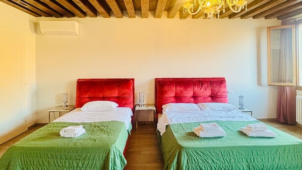 A hotel room with two beds, a chandelier, wooden ceiling beams, and a window with curtains. - Room 'Ca Pisani Su Canal Grande Azzuro' with Wi-Fi (Venice)