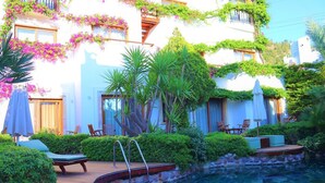 A poolside area with a wooden deck, lounge chairs, and a stone wall. - Munahan Hotel Bodrum (Bodrum)