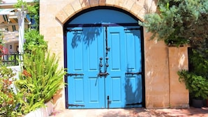 A blue door with a metal handle, set within a stone archway, surrounded by greenery. - Munahan Hotel Bodrum (Bodrum)