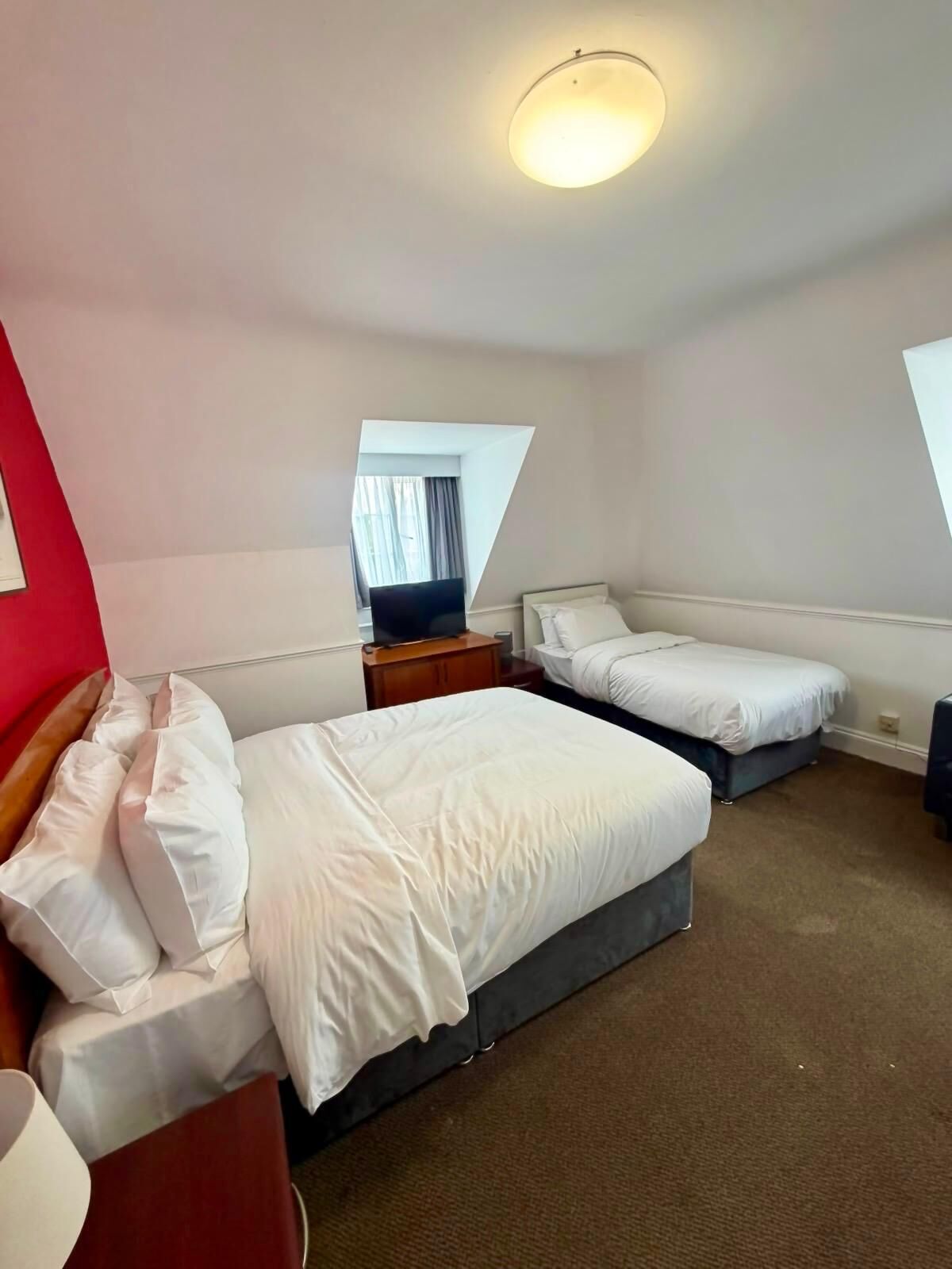 Ein Hotelzimmer mit zwei Betten, einem Schreibtisch, einem Stuhl und einem Spiegel.
