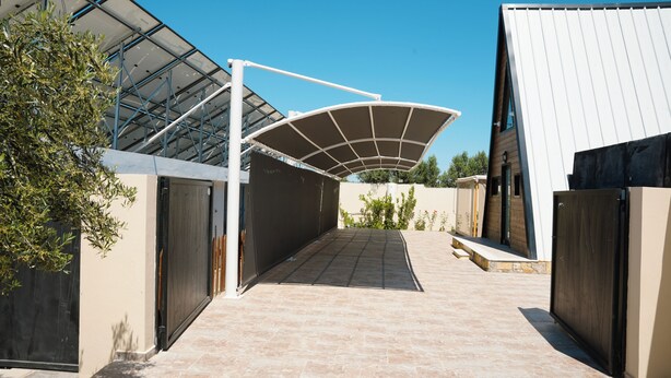 A covered outdoor area with a curved roof, a paved walkway, and a gate leading to a building. - Dar Jana et Dar Jad (Ben Khiar Diar Ben Salem)