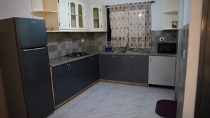 Una cocina compacta equipada con refrigerador, estufa, microondas y armarios.