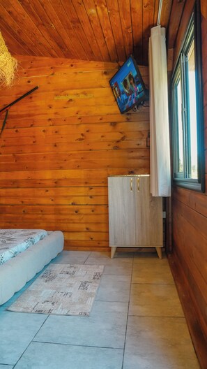 L’intérieur d’une cabine comprenant un lit, un placard, un tapis et un tableau accroché au mur.