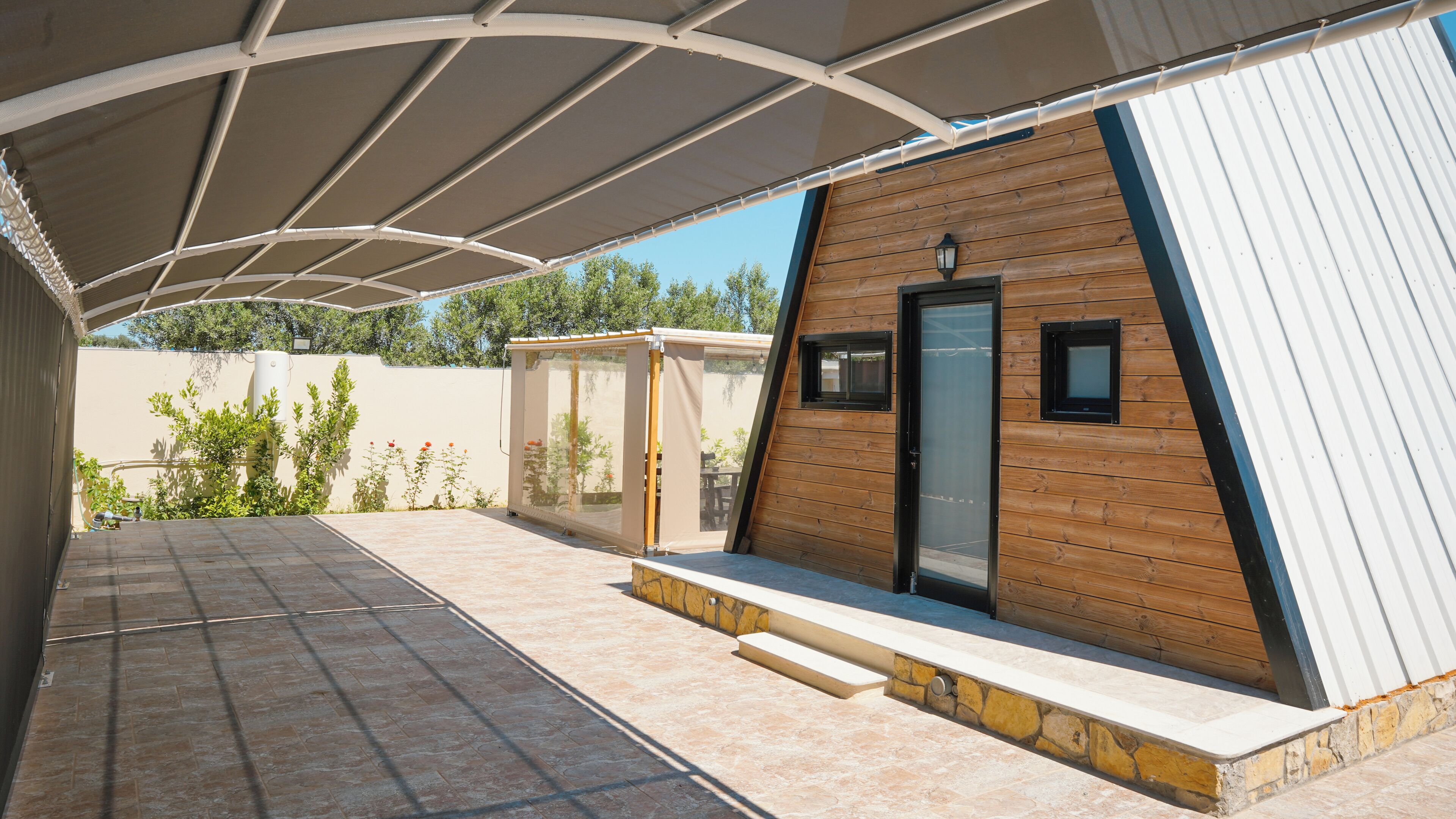 Un espacio al aire libre cubierto con un edificio de estilo cabaña de madera, una puerta de vidrio y un ventanal pequeño.