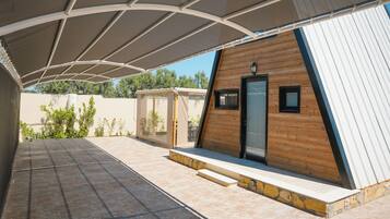 Un espacio al aire libre cubierto con un edificio de estilo cabaña de madera, una puerta de vidrio y un ventanal pequeño.