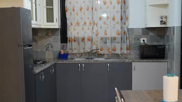 Una cocina con refrigerador, microondas y una mesa de comedor con sillas.