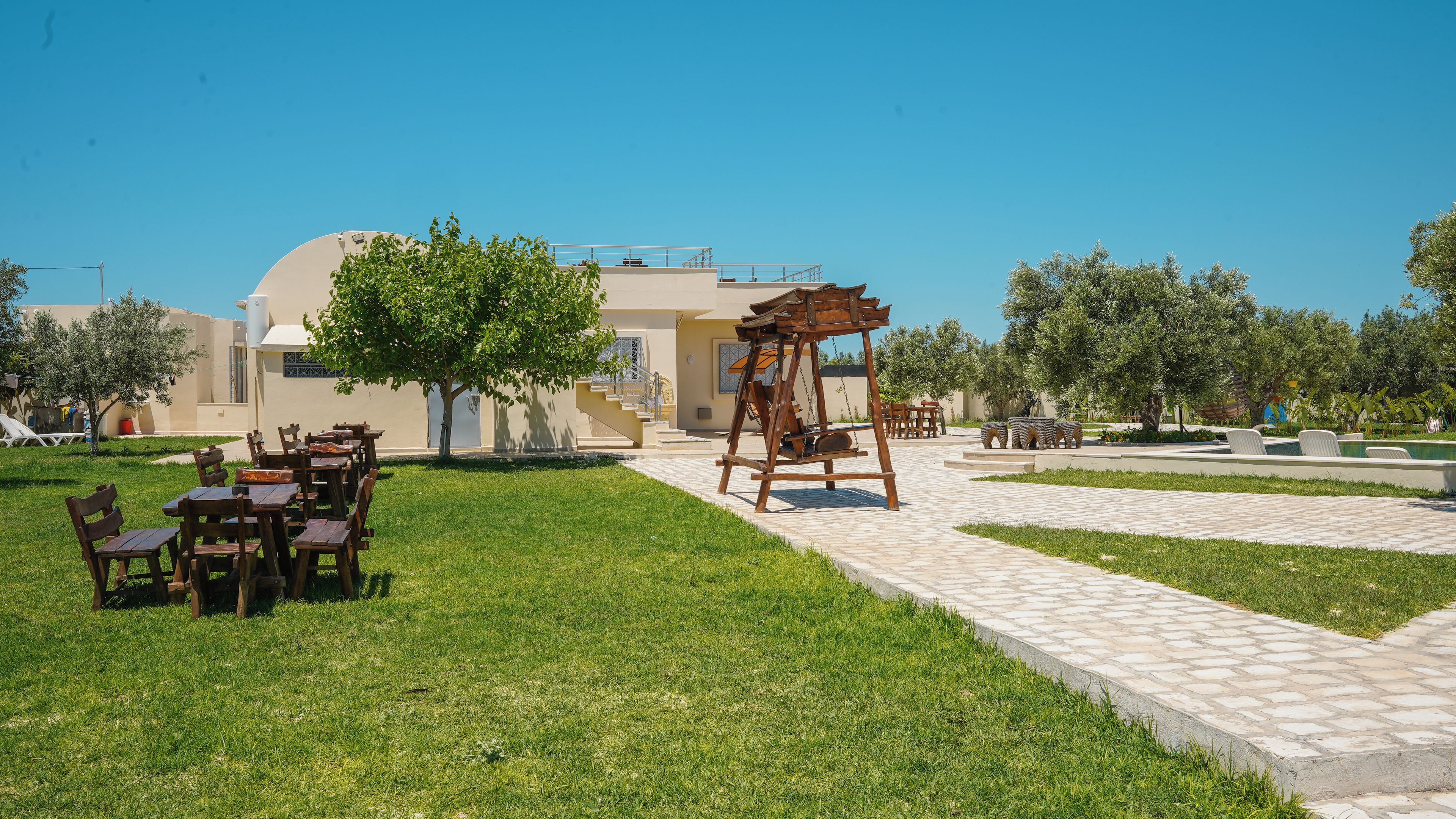 A courtyard with outdoor seating, a swing set, and a pool area.